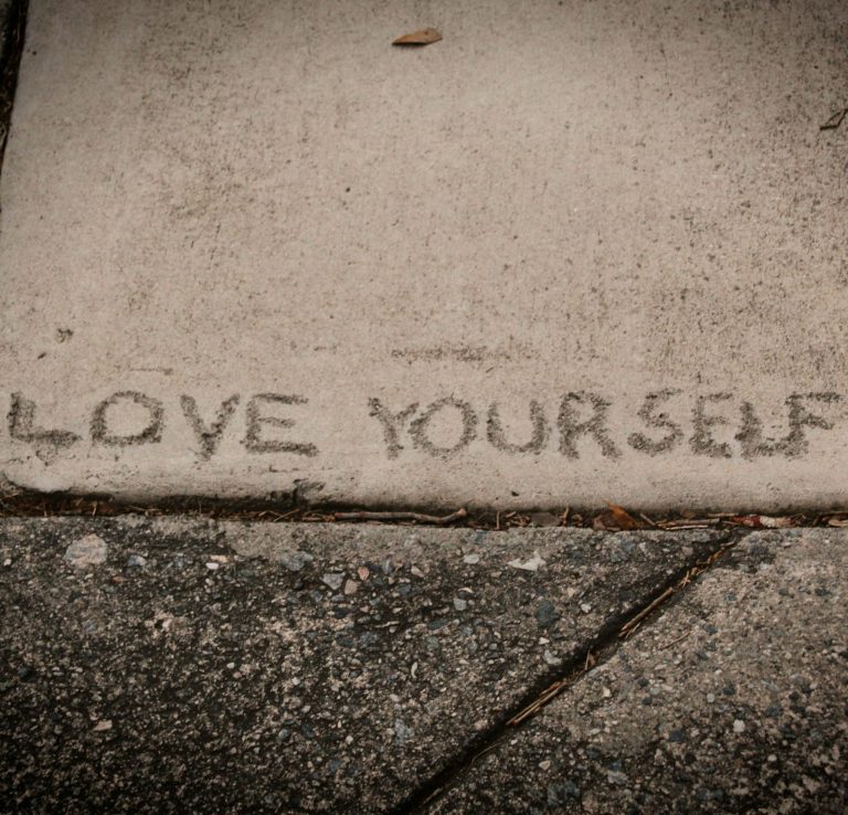 A message worth returning to "Love yourself" written in dried cement, self-esteem counselling Exeter